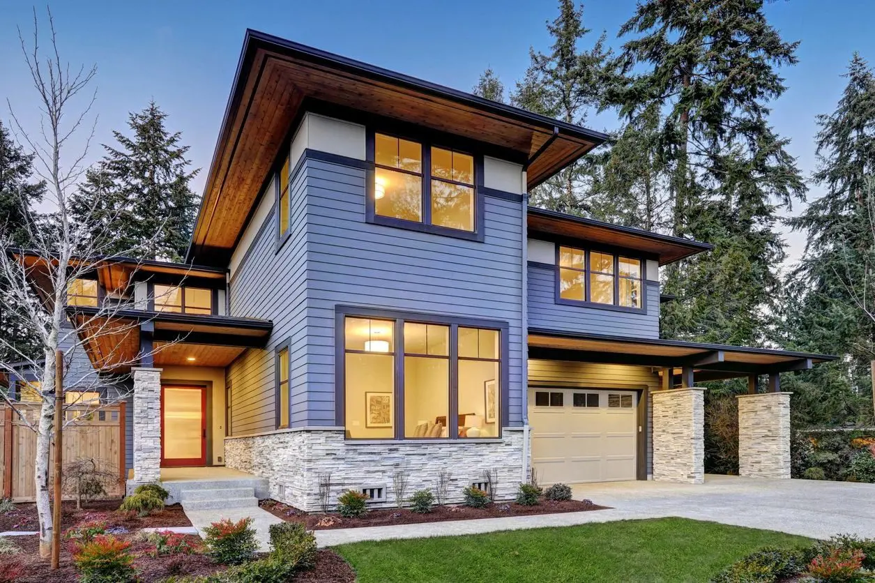 A blue house with a stone front and side of the house.