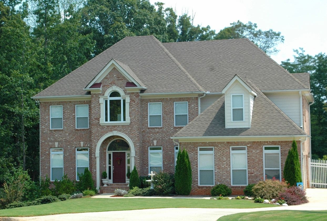 A large brick house with trees in the background.